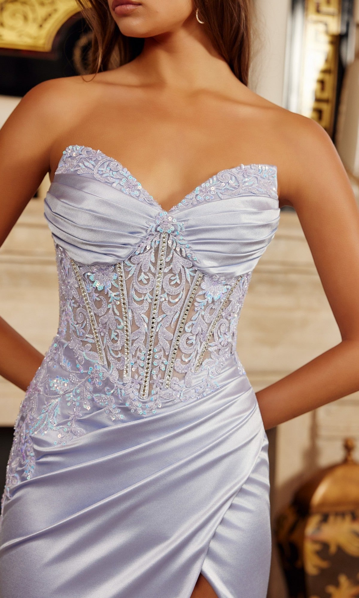 A woman models the Nox Anabel H1876 long prom dress, a strapless lavender satin gown with a fitted corset bodice, embroidered lace details, and a high-slit floor-length skirt.